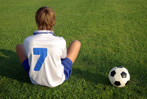 boy sitting on sidelines at soccer match